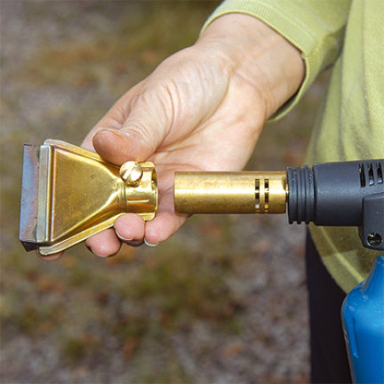 En blæsebrænder udstyret med en flad dyse (eller en varmepistol) blødgør malingen